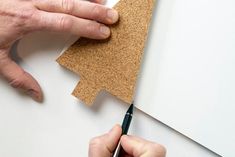 a person cutting out a piece of cork with a pair of scissors