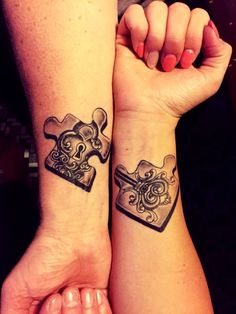 two people with matching tattoos on their arms holding up puzzle pieces that look like hearts