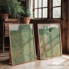 two framed paintings sitting on top of a wooden floor next to a potted plant