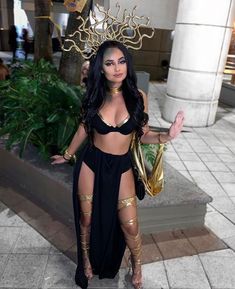 a woman in a black and gold costume posing for the camera with her hands out