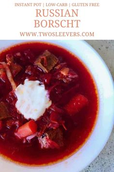 a white bowl filled with red soup and topped with sour cream on top, sitting on a table