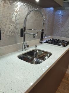 a kitchen counter with a sink and faucet next to a stove top oven