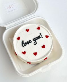 a cake with the words love you written on it in a foam container next to a plastic container