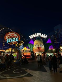 an amusement park at night with people walking around