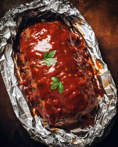 meatloaf covered in sauce and garnished with parsley on aluminum foil