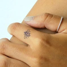 a woman's hand with a small bee tattoo on it