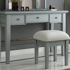 a gray vanity with a stool and mirror