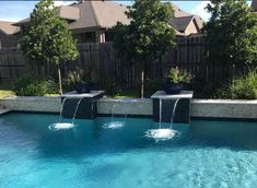 an outdoor pool with water features in the center and two fountains running down it's sides