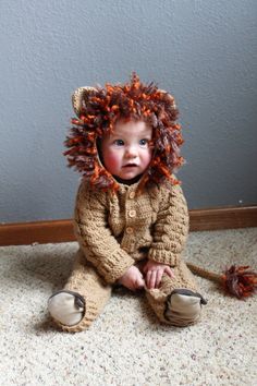 a baby wearing a lion costume sitting on the floor