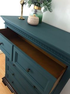 a blue dresser with drawers and a potted plant on top