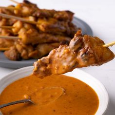 chicken skewers being dipped with dipping sauce