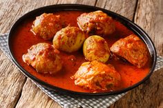 some meatballs are in a red sauce on a wooden table with a checkered napkin