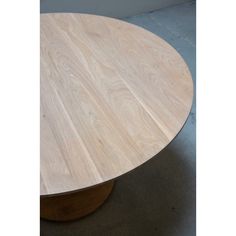 a round wooden table sitting on top of a cement floor