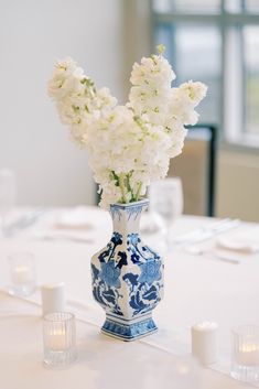 white flowers in a blue and white vase on a table