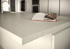 an open book sitting on top of a kitchen counter next to ovens and cabinets