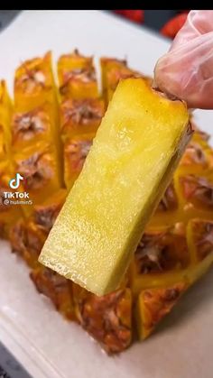 someone is holding a piece of pineapple on top of some other food in front of them