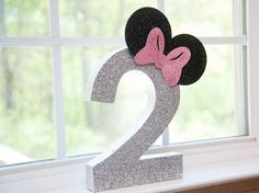 a minnie mouse head with a pink bow on it's head sitting in front of a window