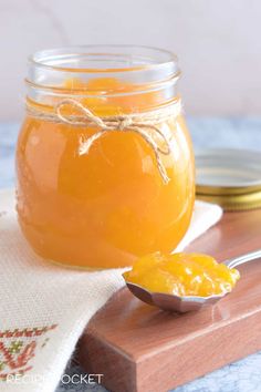 a glass jar filled with liquid sitting on top of a wooden table next to a spoon