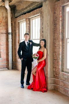 a man and woman standing next to each other in front of brick walls with windows