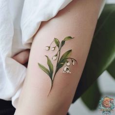 lily of the valley tattoo on the right thigh and upper arm, with green leaves