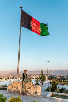 a man standing next to a flag on top of a stone wall