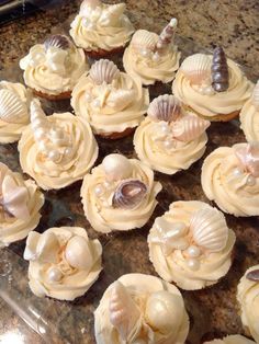 cupcakes with shells and seashells on them sitting on a counter top