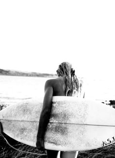 a woman carrying a surfboard on the beach