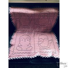 a pink crocheted blanket sitting on top of a table