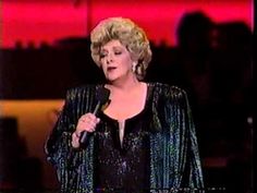 the woman is holding a microphone in her right hand and wearing a black dress with sequins on it