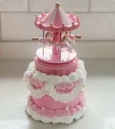 a pink carousel cake with white flowers on top