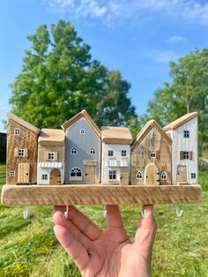 a hand holding up a wooden model of houses