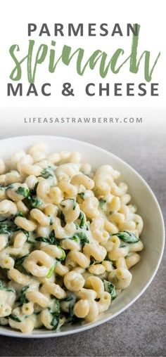 a white bowl filled with macaroni and cheese covered in spinach on top of a table