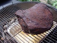 a large piece of meat is cooking on a bbq grill with some bread in it