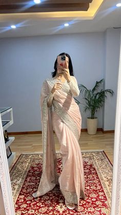 a woman taking a selfie in a mirror wearing a sari and holding a camera