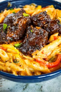 a blue bowl filled with pasta and meat covered in marinara sauce on top of a marble counter