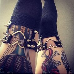 two legs with tattoos and chains on them, one is wearing black socks while the other has