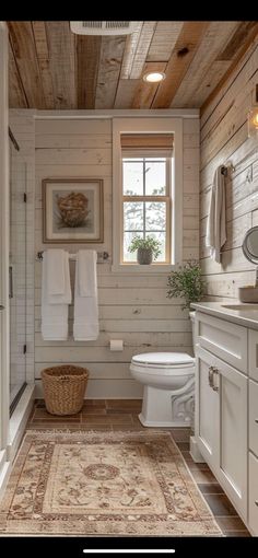 a white bathroom with wood paneling and a rug on the floor next to the toilet