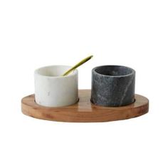 two marble bowls on a wooden tray with a spoon in one bowl and another stone cup next to it