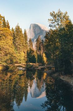 a lake surrounded by trees with a mountain in the background