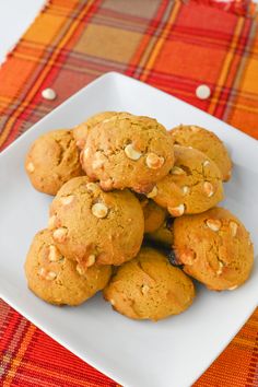 a white plate filled with cookies on top of a red and yellow table cloth next to a glass of milk