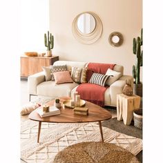 a living room filled with lots of furniture next to a wall mounted round mirror and potted plants