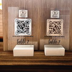 two wooden plaques with qr - code designs on them, one for each table