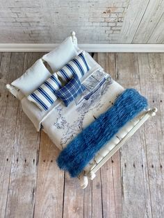 an upholstered bed with blue and white pillows on top of wooden flooring