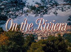 a sign that reads on the rivera in front of some trees and buildings with mountains in the background