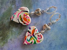 White Polymer Clay Heart Beads with Multicolor Swirled Designs accented with Small Silver Metal Heart Connectors and Silver Metal Beads.  Earrings measure 1.5". Multicolor Heart Charm Earrings For Valentine's Day, Multicolor Heart Earrings With Charm For Valentine's Day, Multicolor Heart Charm Dangle Earrings, Multicolor Heart-shaped Earrings With Heart Beads, Nickel-free Multicolor Heart Earrings, Multicolor Nickel-free Heart Earrings, Handmade Multicolor Heart Earrings, Multicolor Dangle Earrings With Heart Beads, Multicolor Heart Beads Earrings For Valentine's Day