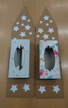 two cardboard boxes with white stars on them and one has a paper cutout in the shape of a house