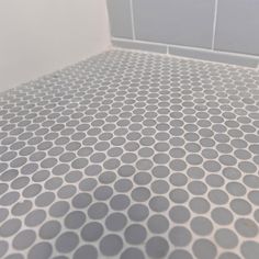 a white and gray tiled bathroom floor with circles on it's grouting