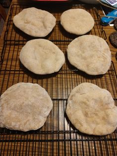 four uncooked pizzas sitting on top of a cooling rack next to cookies