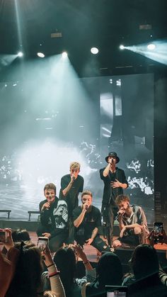 group of young men on stage with one holding his hand up in the air while others look on