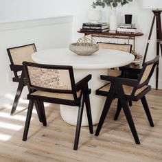 a white table with four chairs and a bowl on top of it in the middle of a room